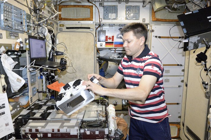 Cosmonaut Oleg Kononenko with a bioprinter at the ISS during a space experiment titled Magnetic 3D Bioprinter